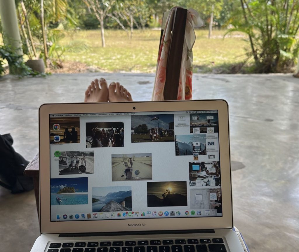 Läppäri jalkojen päällä, taustalla pihaa ja puita