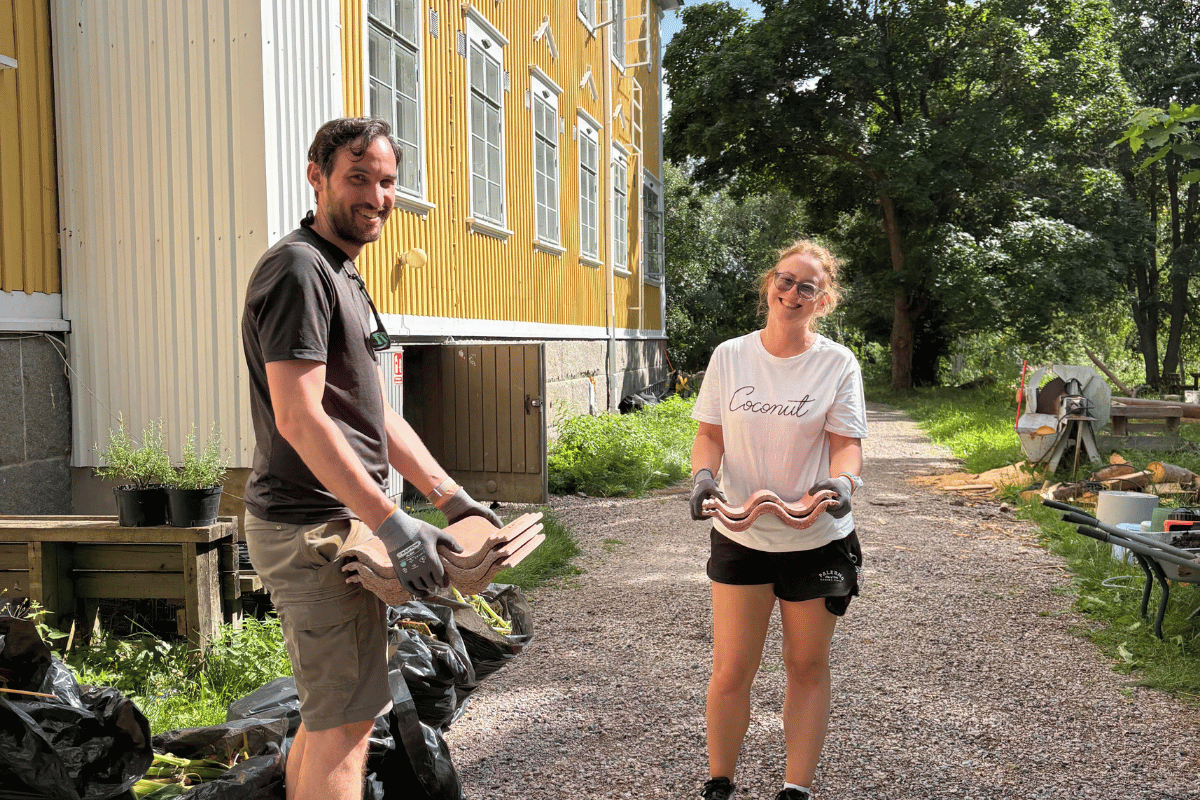 Kaksi ihmistä seisoo kartanon edessä käsissään tiiliä